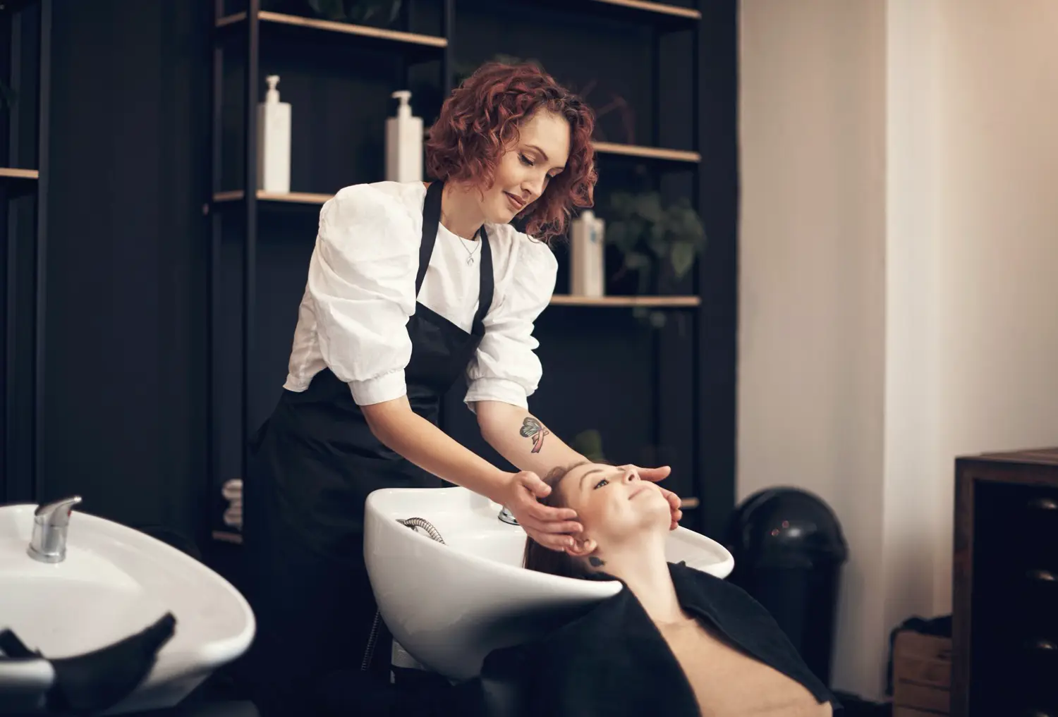 Hairdresser washing a client’s hair in a modern salon.